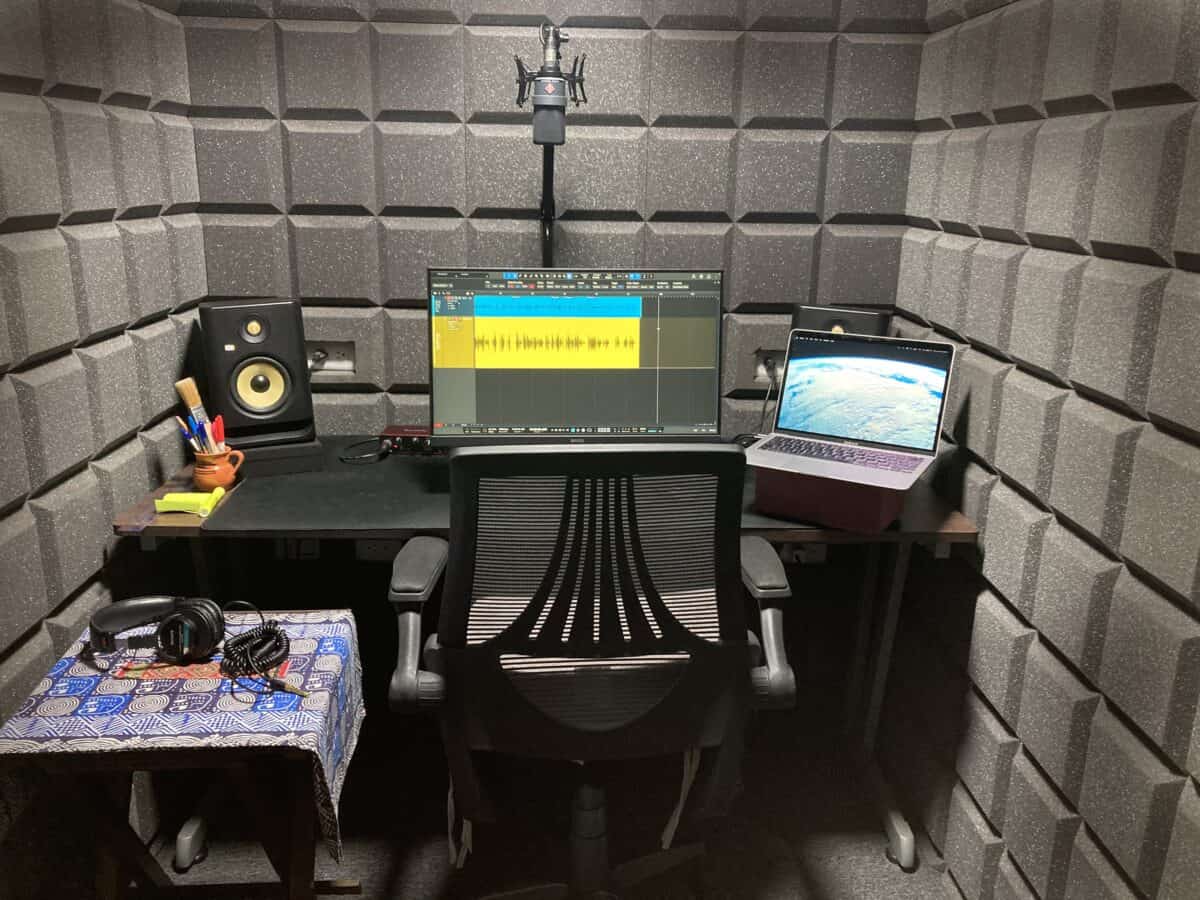 Colette's recording studio containing a desk, chair, laptop computer, an additional wide screen monitor, microphone, and various pieces of recording equipment