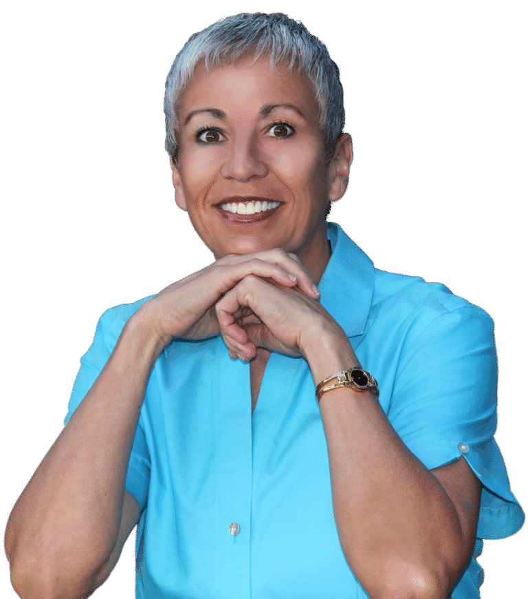 Colette sitting, wearing a light blue shirt and looking at the camera with her hands closed under her chin.